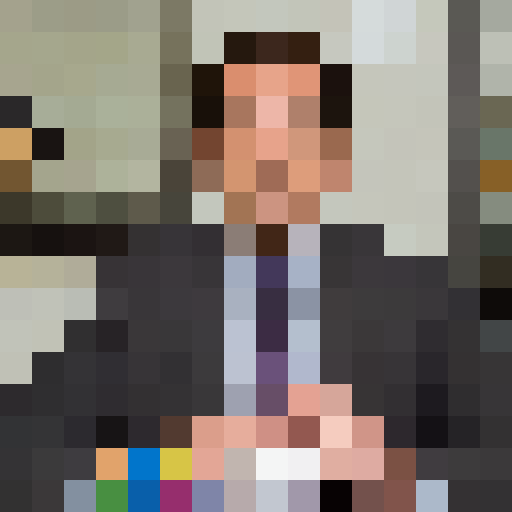 Middle-aged Caucasian male with receding dark hair, dressed in a business suit. Expressive eyebrows and a slightly bemused expression